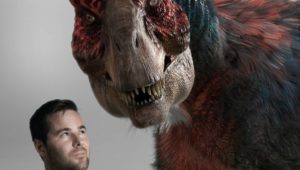 Photo of Matt Drummond posing with the VFX model of T. rex he rendered for his debut film, Dinosaur Island.